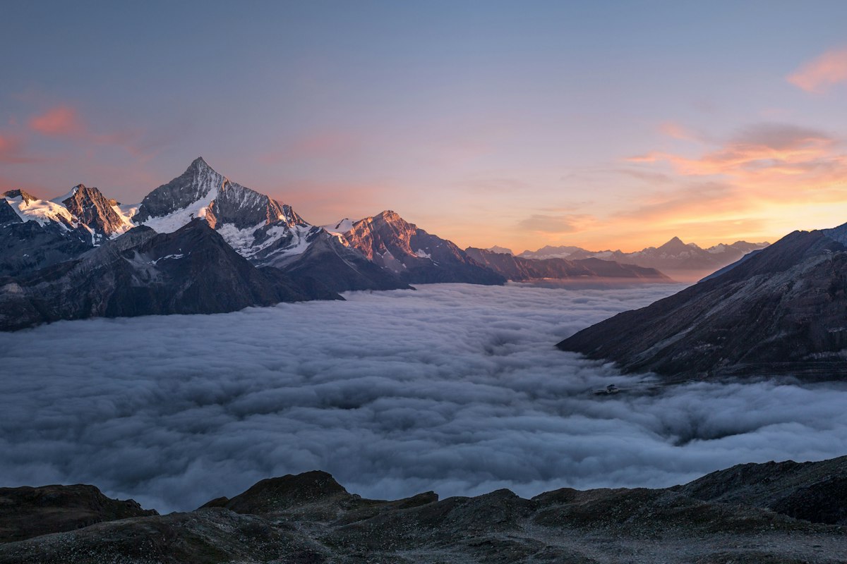 Sommets alpins au-dessus d'une mer de nuages au lever du soleil